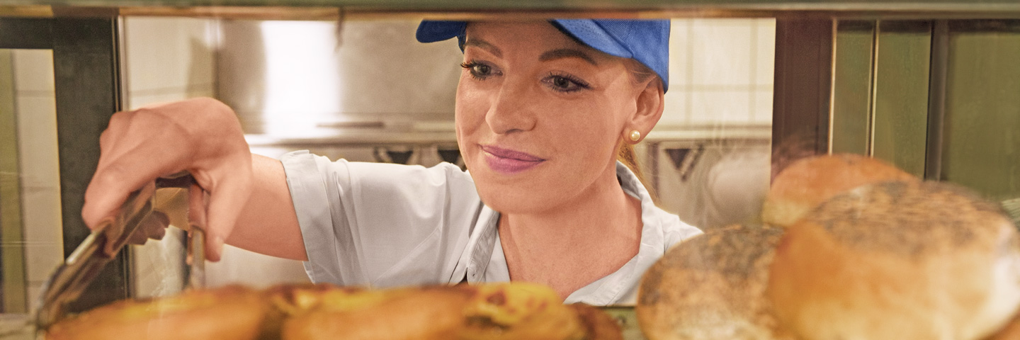 Minijobs: Eine Verkäuferin greift mit einer Zange nach Gebäck Minijobs: Eine Verkäuferin greift mit einer Zange nach Gebäck